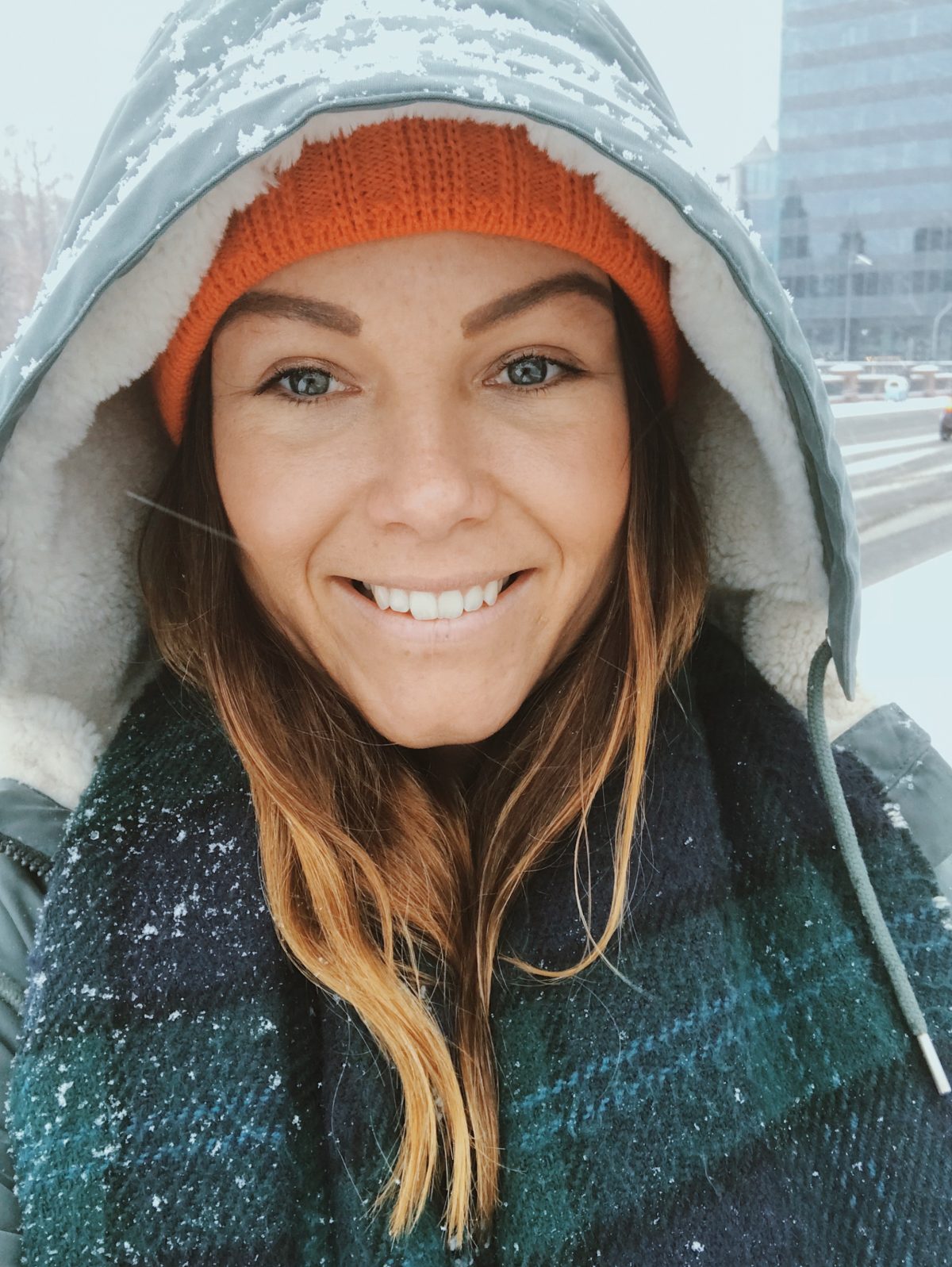 A girl smiling in the snow, wearing outdoor gear