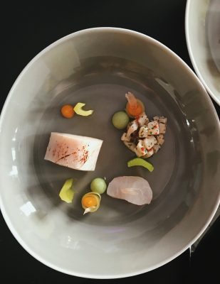 A plate of gourmet food: the bowl is gray and the ingredients are sparsely presented in individual pieces.